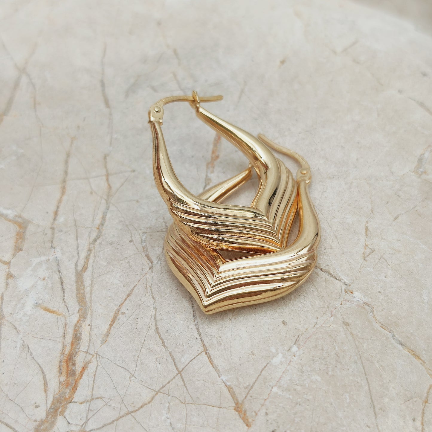 Close-up van vintage 9ct gold hoop earrings UnoAErre met ribbelstructuur