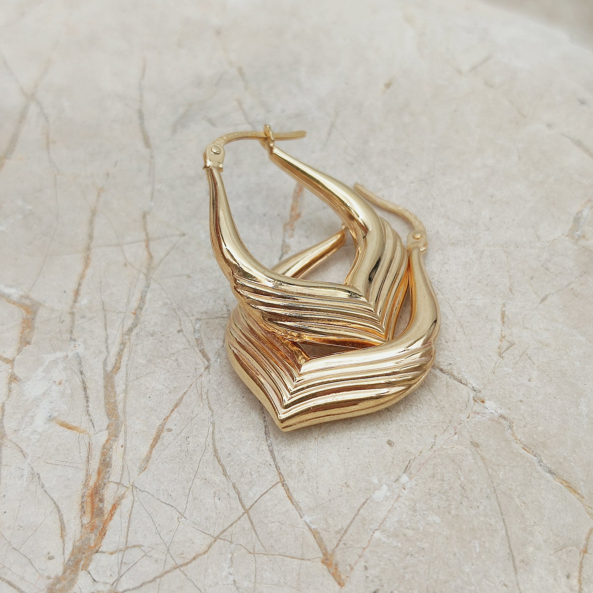 Close-up van vintage 9ct gold hoop earrings UnoAErre met ribbelstructuur