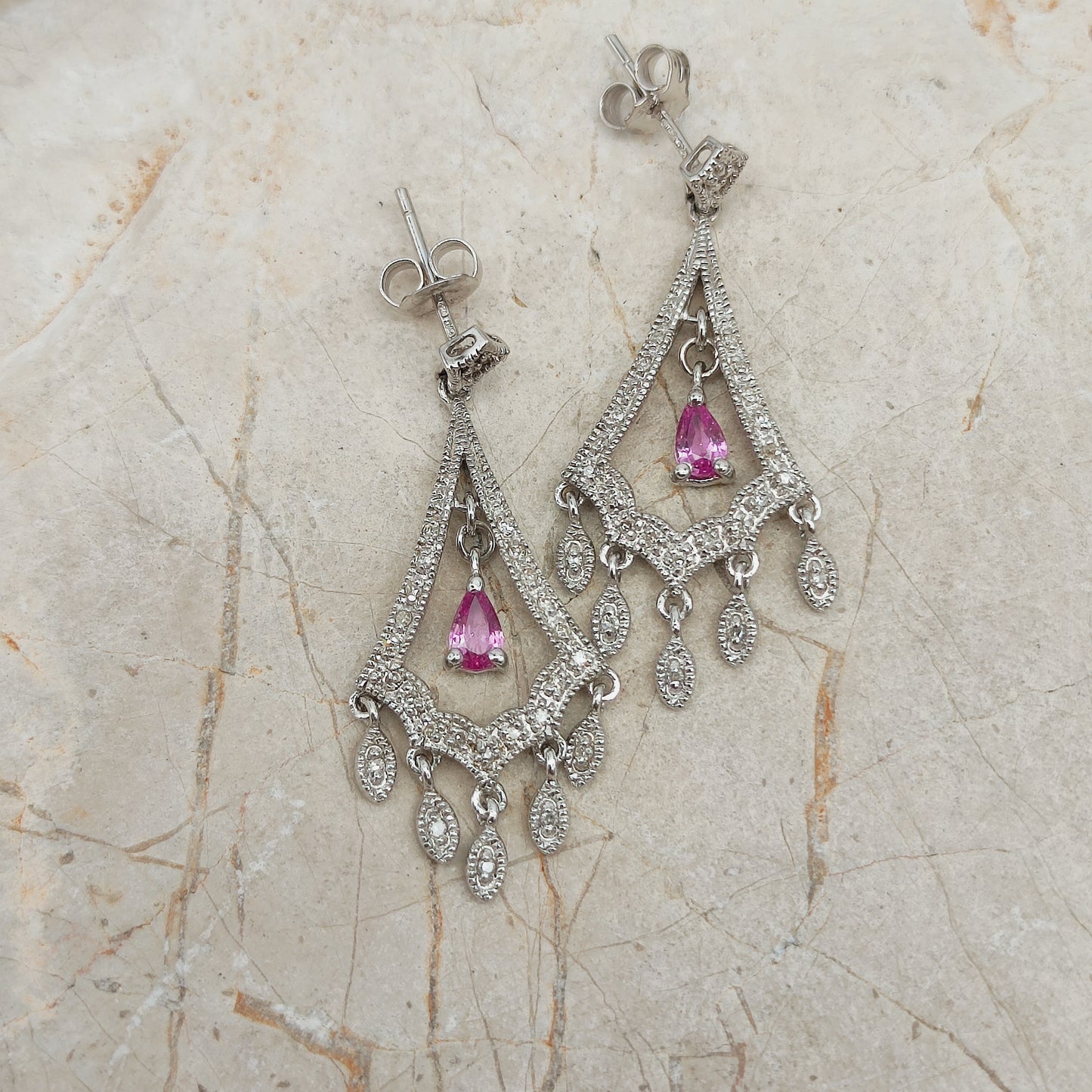 Detail van witgouden oorbellen met bewegende diamant hangers