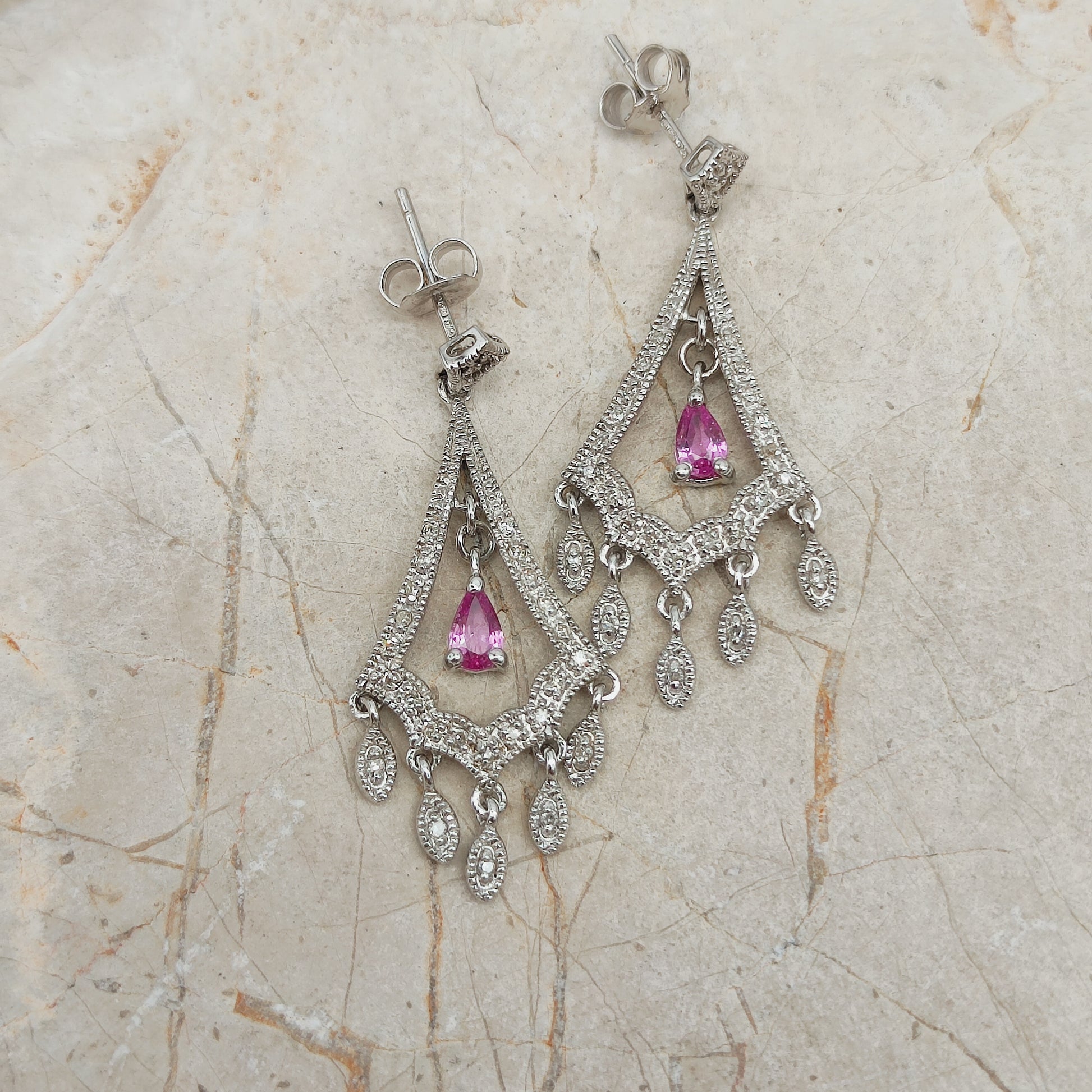 Detail van witgouden oorbellen met bewegende diamant hangers