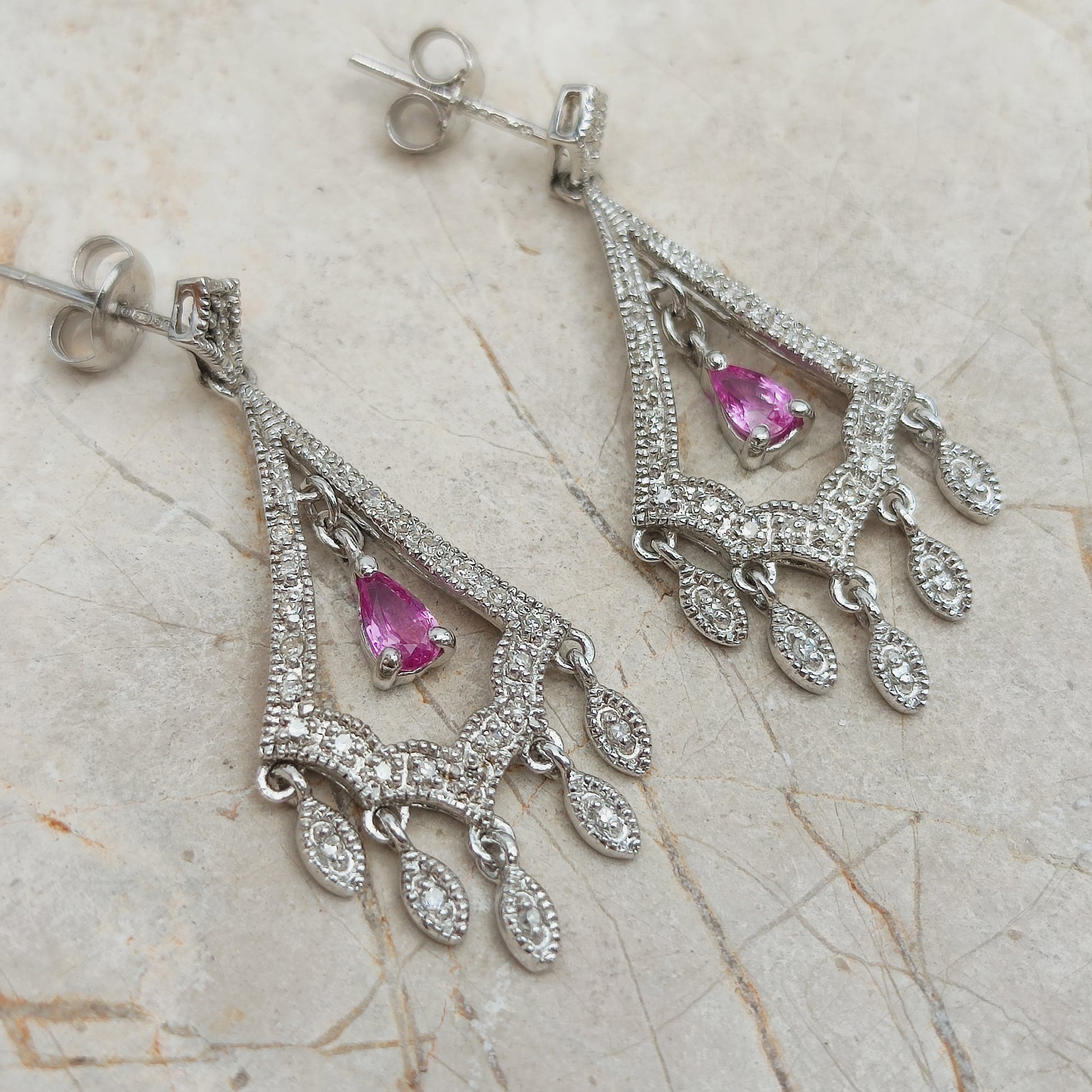 Close-up van chandelier oorbellen met roze saffier