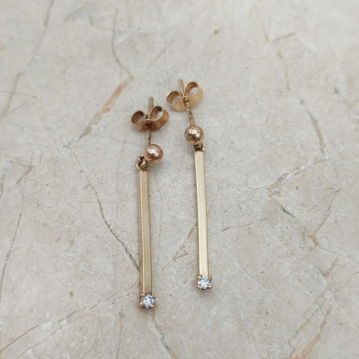 Minimalistische vintage gouden oorbellen met diamant op stenen achtergrond