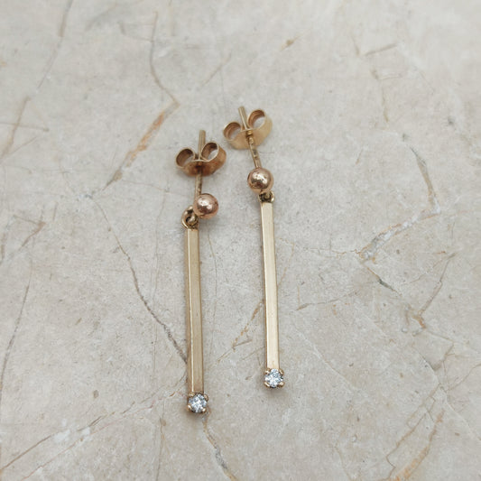 Minimalistische vintage gouden oorbellen met diamant op stenen achtergrond