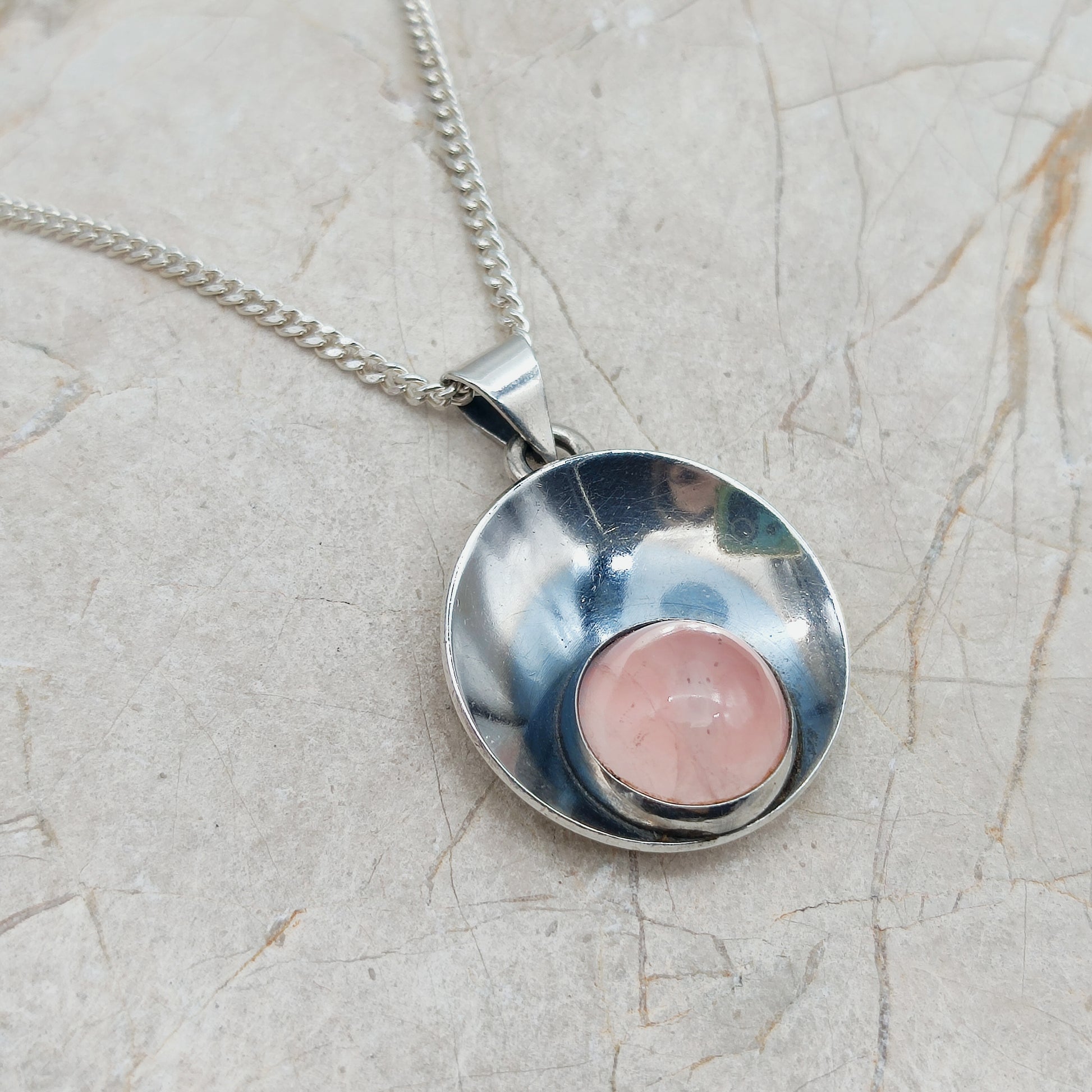 Zilveren hanger met rozekwarts en ketting op lichte achtergrond