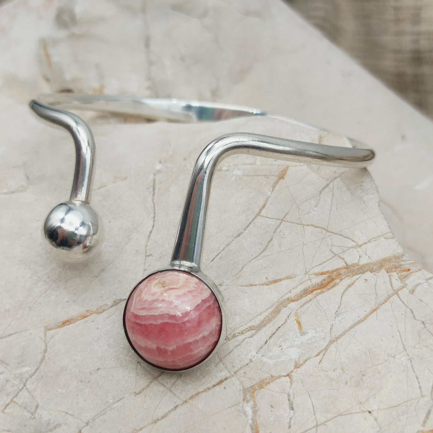 Detail van zilveren armband met bol en rhodochrosiet steen