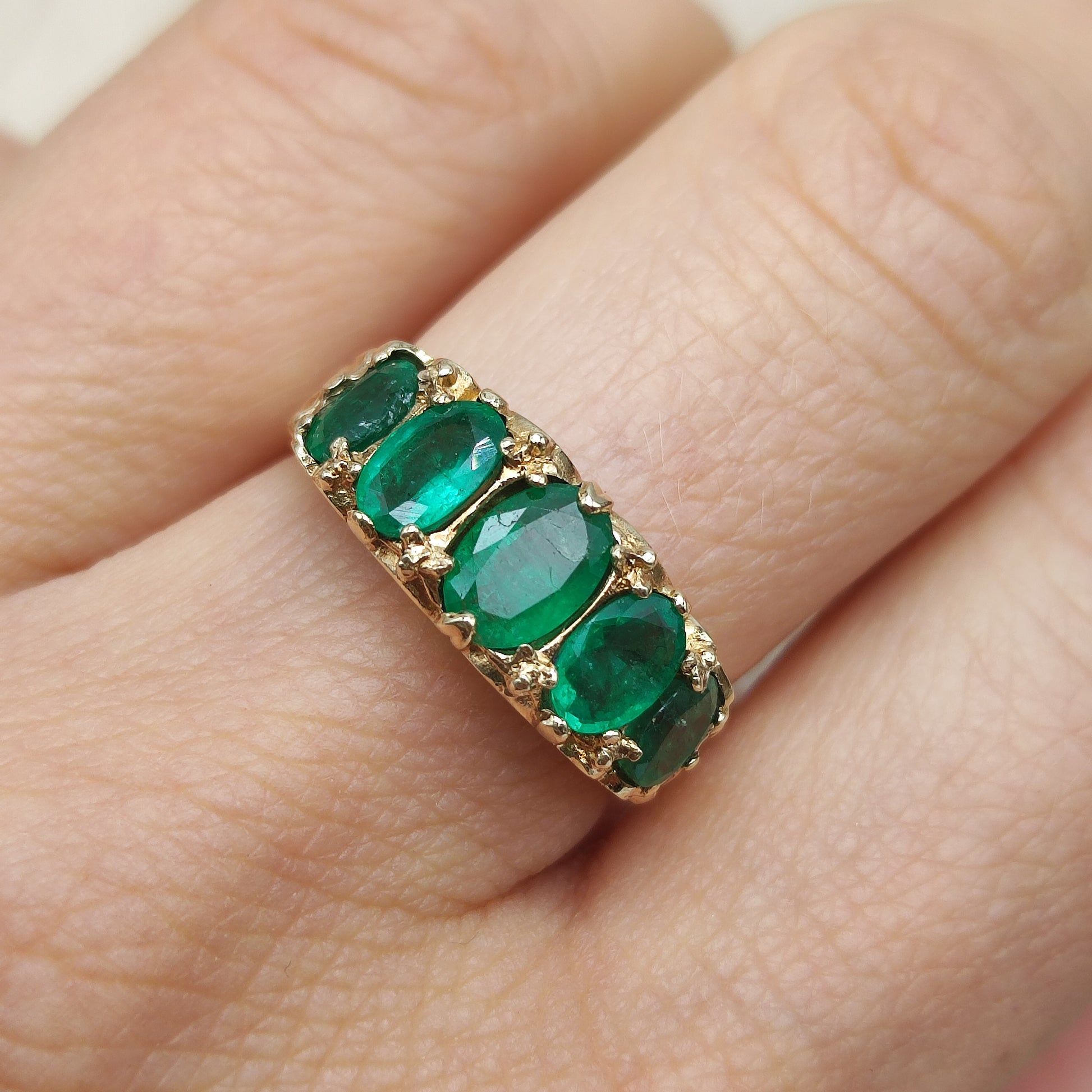 Vintage gouden ring met ovale smaragden gedragen aan de hand