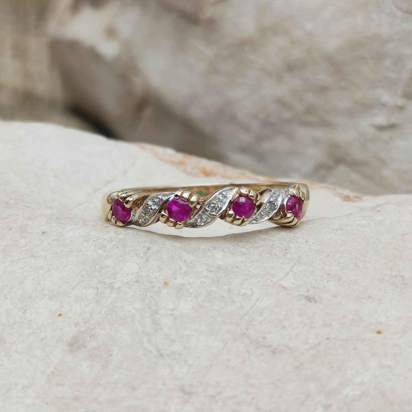 Detail van vintage geelgouden ring met robijn, diamantaccenten en golvend patroon