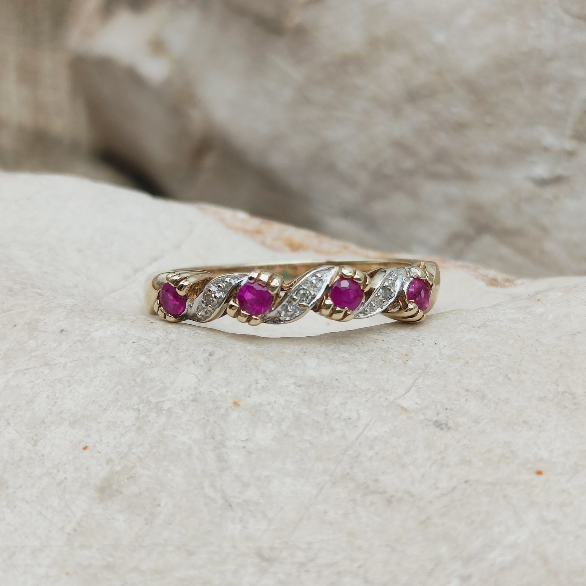 Detail van vintage geelgouden ring met robijn, diamantaccenten en golvend patroon