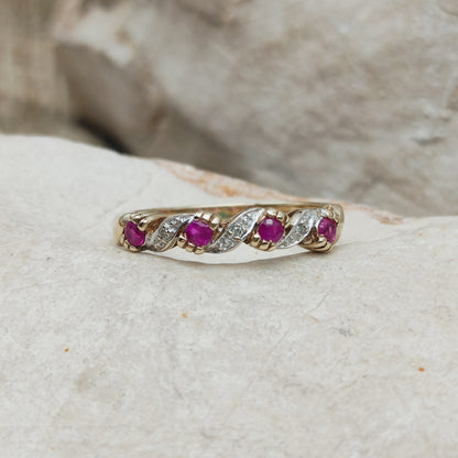 Detail van vintage geelgouden ring met robijn, diamantaccenten en golvend patroon