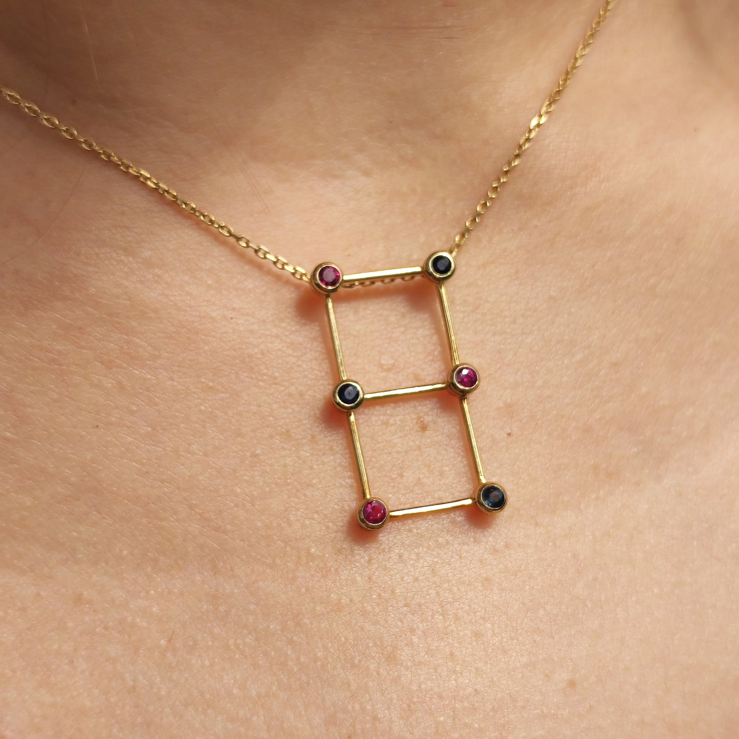 Vintage Franse gouden ketting met geometrische hanger bezet met saffieren en robijnen gedragen rond de hals