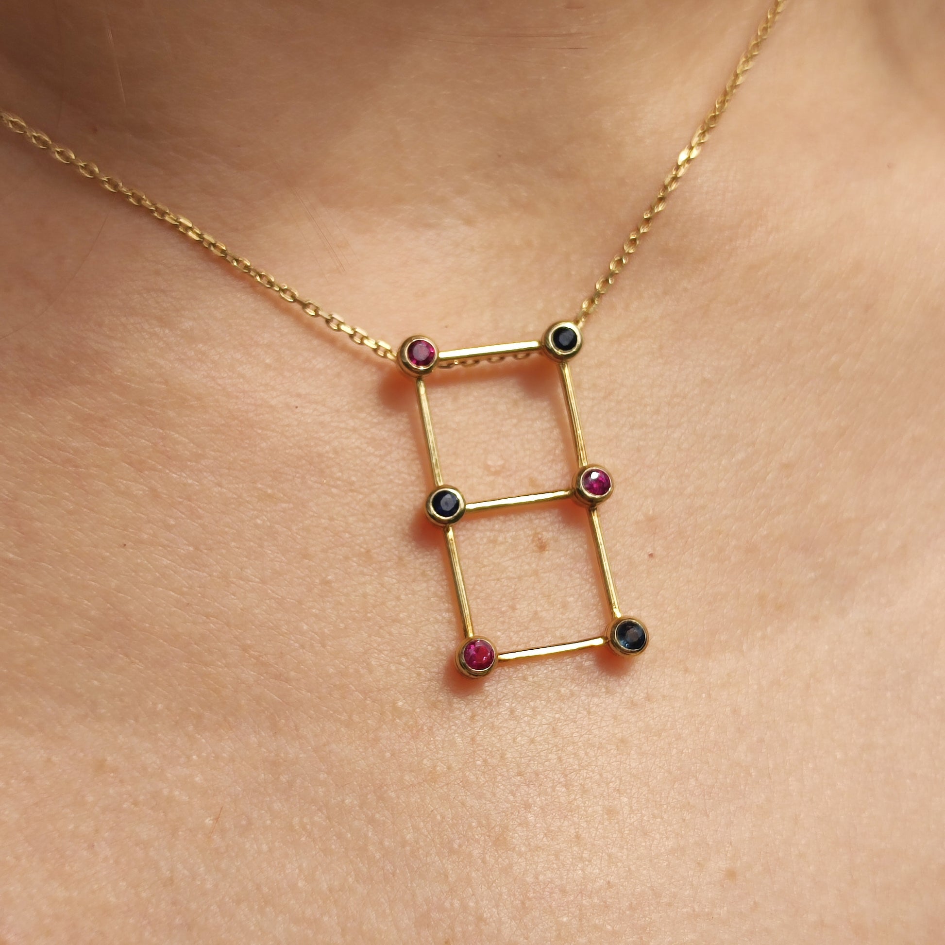 Vintage Franse gouden ketting met geometrische hanger bezet met saffieren en robijnen gedragen rond de hals