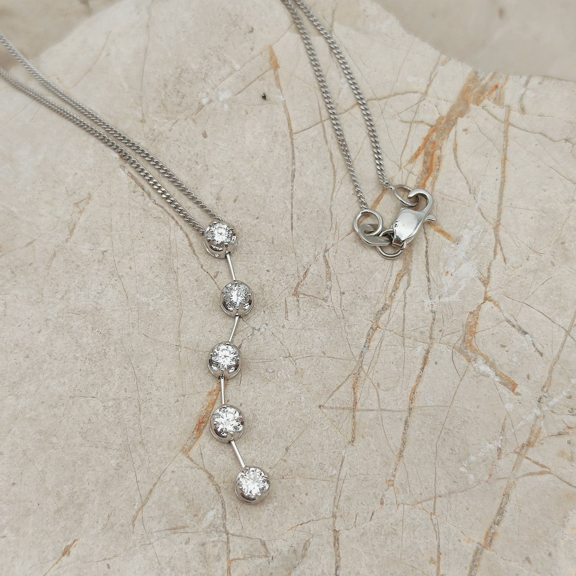 Detail van vintage witgouden hanger met vijf diamanten onder elkaar