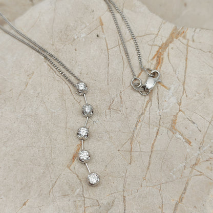 Detail van vintage witgouden hanger met vijf diamanten onder elkaar