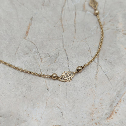 Detail van gouden ketting met decoratief tussenstukje en bolletjes