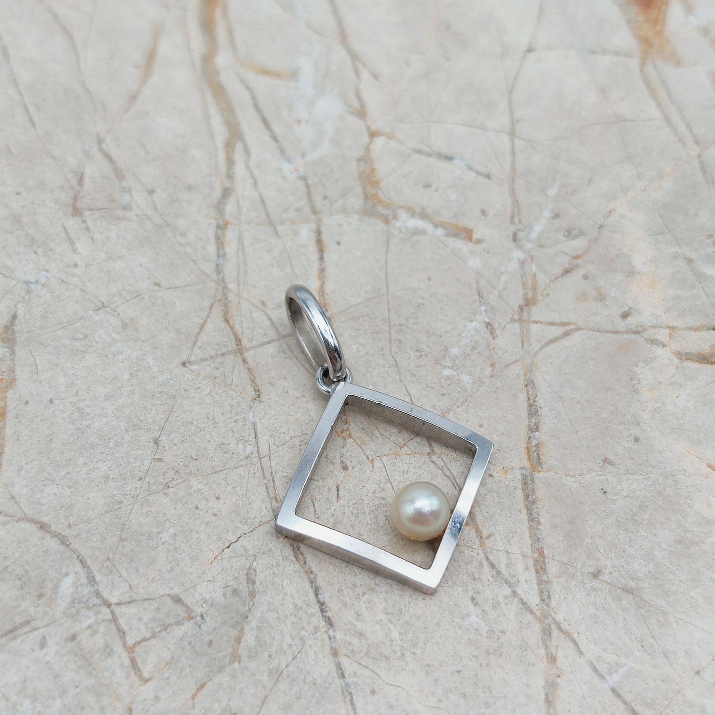 Detail van open geometrische hanger in 18 karaat witgoud met parel