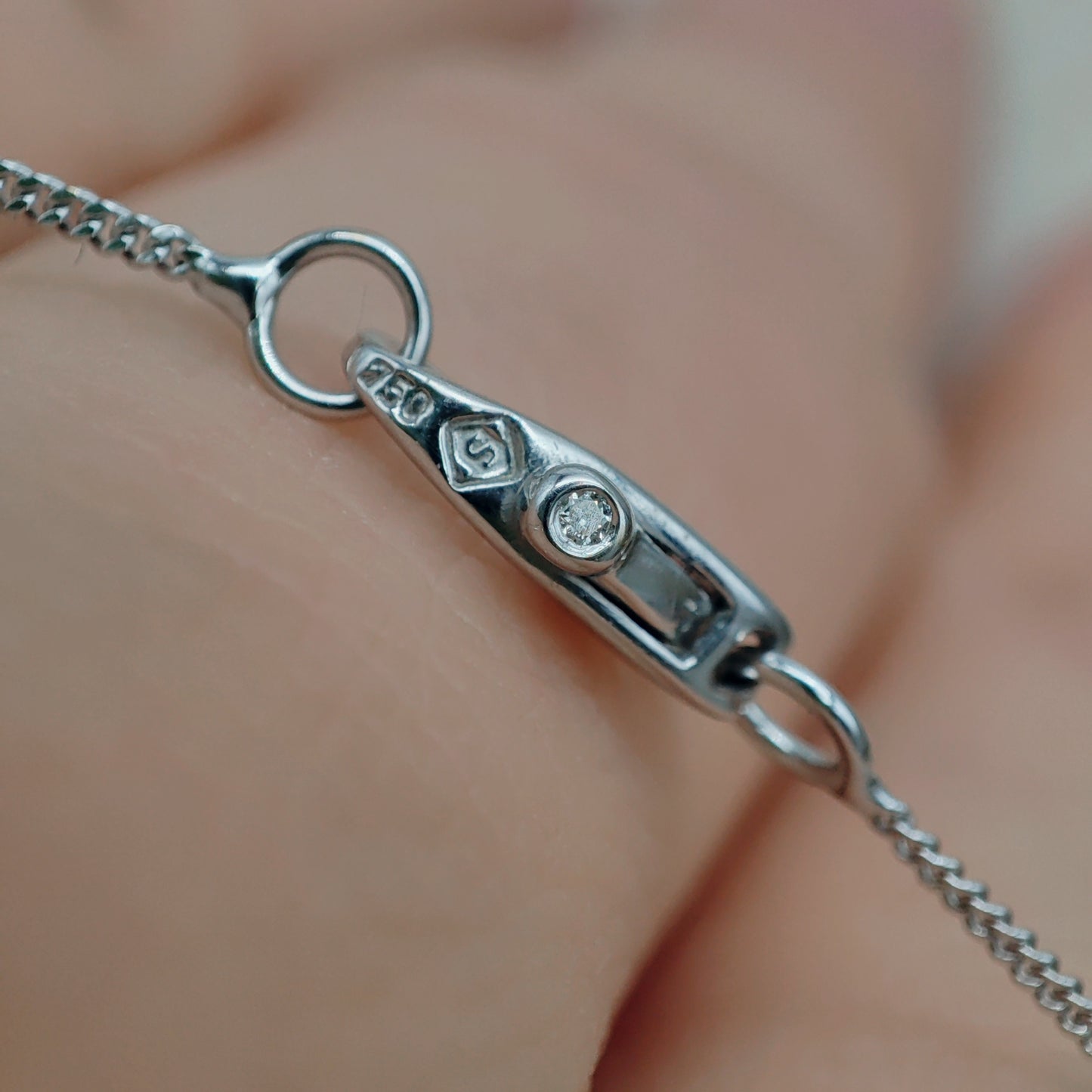 Detail van het langwerpige slotje met kleurloze saffier in witgouden ketting