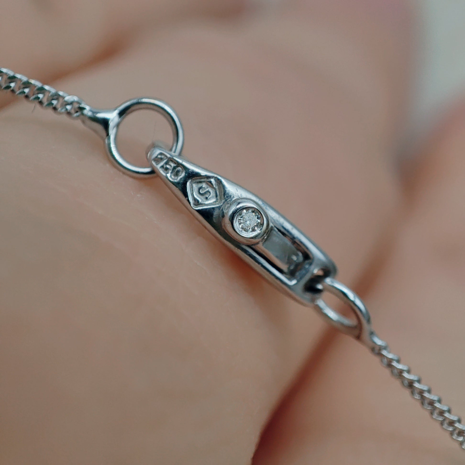 Detail van het langwerpige slotje met kleurloze saffier in witgouden ketting