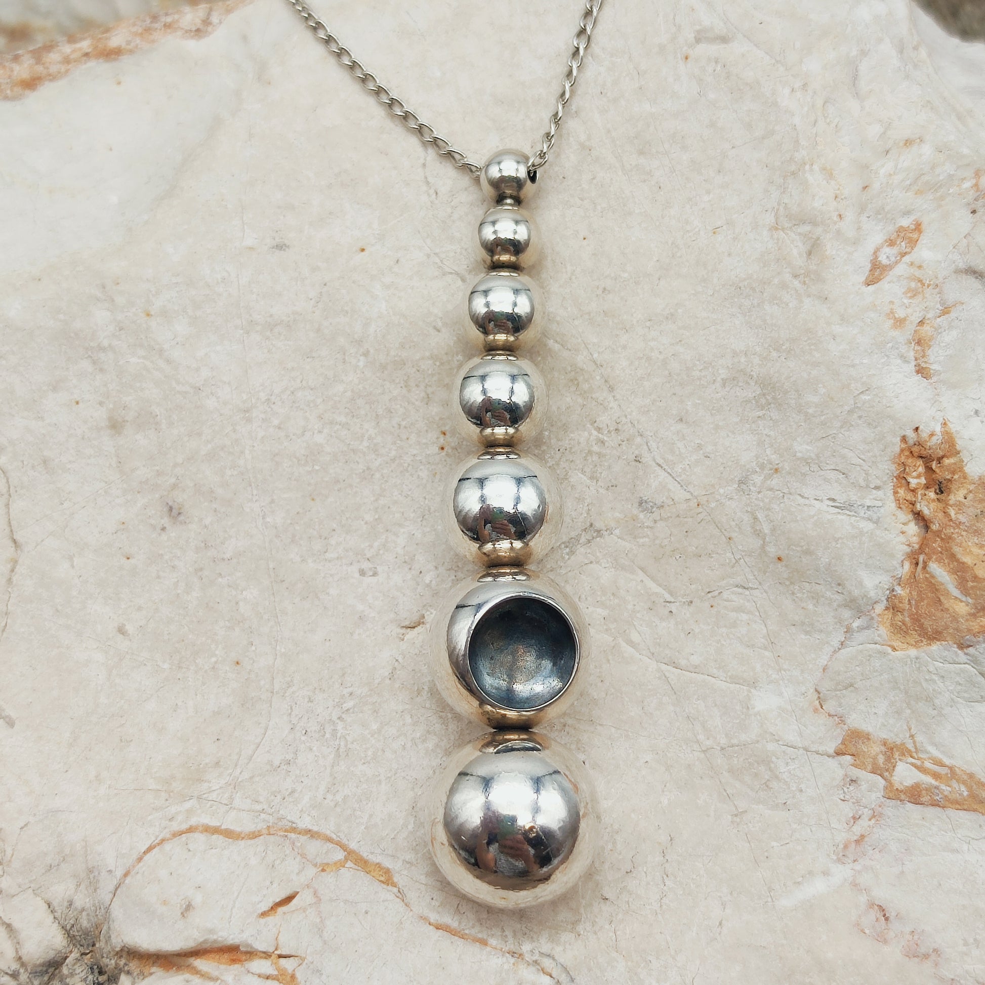 Cave pendant with seven silver spheres and concave crater detail