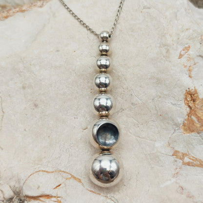 Cave pendant with seven silver spheres and concave crater detail