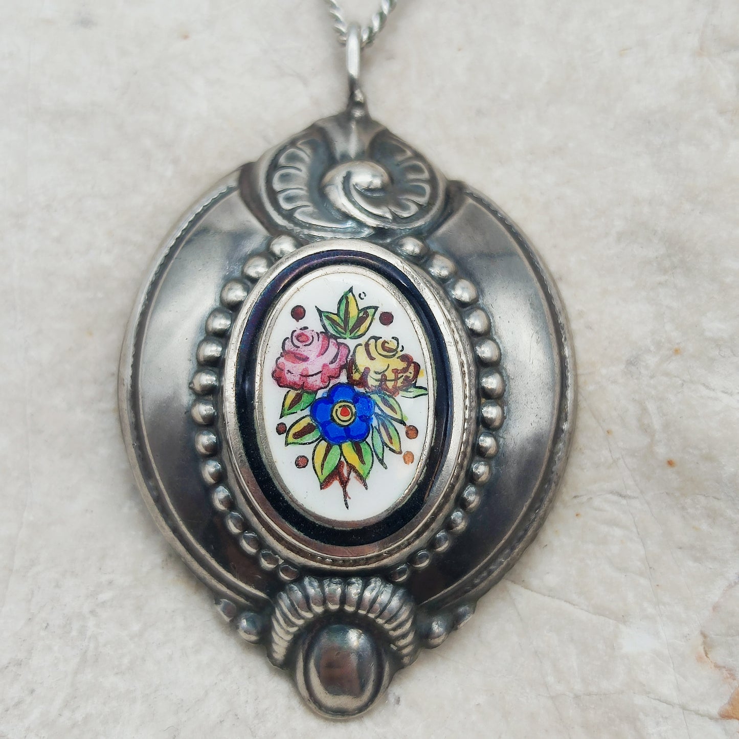 Detail van het handbeschilderde bloemenmedaillon in de antieke zilveren hanger