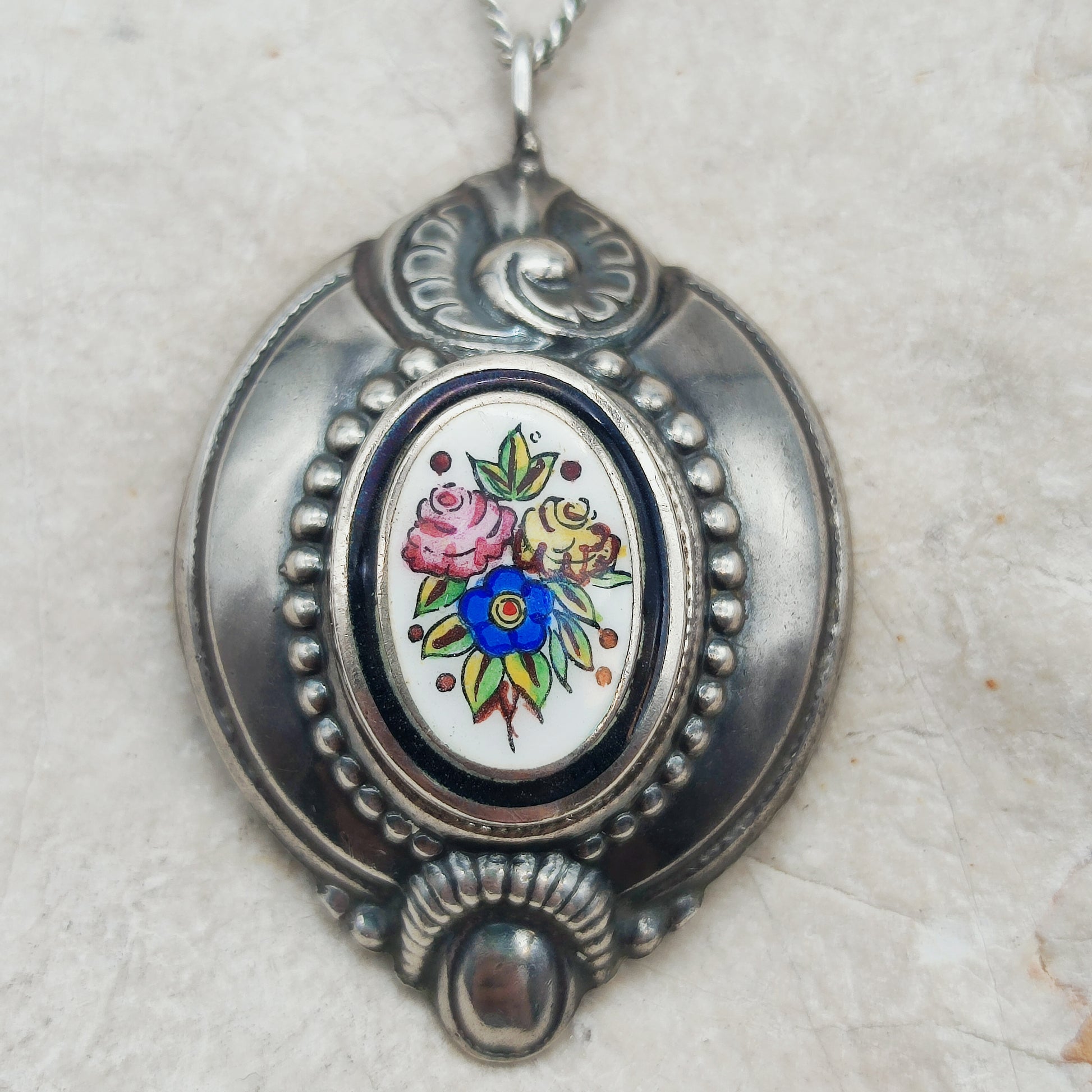 Detail van het handbeschilderde bloemenmedaillon in de antieke zilveren hanger