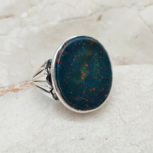 Vintage zegelring in zilver en 9 karaat goud met een grote ongegraveerde blauwgroene heliotroop met rode spikkels en sierlijke waaiervormige schouders.