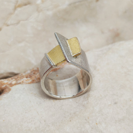 Hedendaagse brede ring in gematteerd 925 zilver met een asymmetrisch gevouwen ontwerp en een rechthoekig detail in 18-karaats goud.