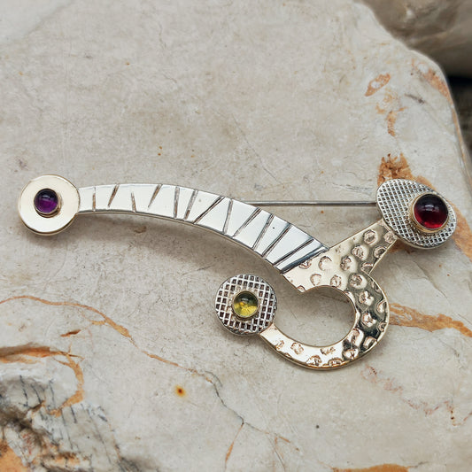 Abstracte zilveren broche met gouden details en cabochons van granaat, peridoot en amethist