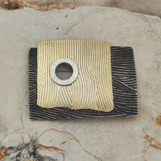 Grote broche en hanger van Jan Suchodolski in geoxideerd 925 zilver met gold wash, golvende lijnstructuur en ronde klinkverbinding.