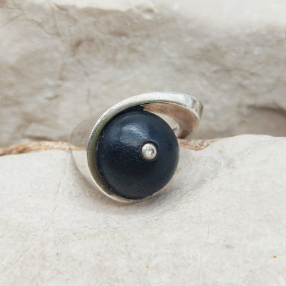 Modernistische sterling zilveren ring met een ovale donkerhouten inzet en een kleine briljant geslepen diamant in het midden.
