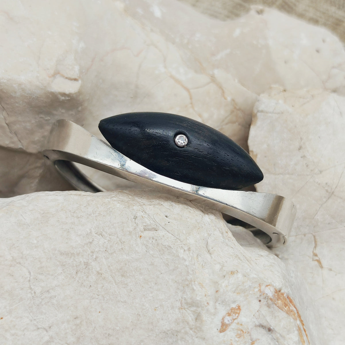Vintage modernistische scharnierarmband in sterling zilver met een navettevormig donkerhouten element en een kleine diamant.