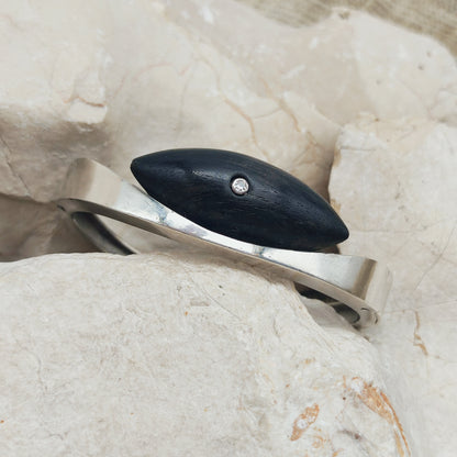 Vintage modernistische scharnierarmband in sterling zilver met een navettevormig donkerhouten element en een kleine diamant.