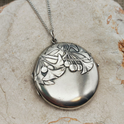Antiek Art Nouveau-medaillon in 800 zilver met ginkgobladeren en vruchten in reliëf, aan een zilveren ketting.