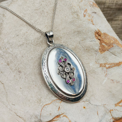 Antiek zilveren medaillon met roosgeslepen diamant, vier robijnen, zaadpareltjes en gegraveerde rand aan een zilveren ketting.