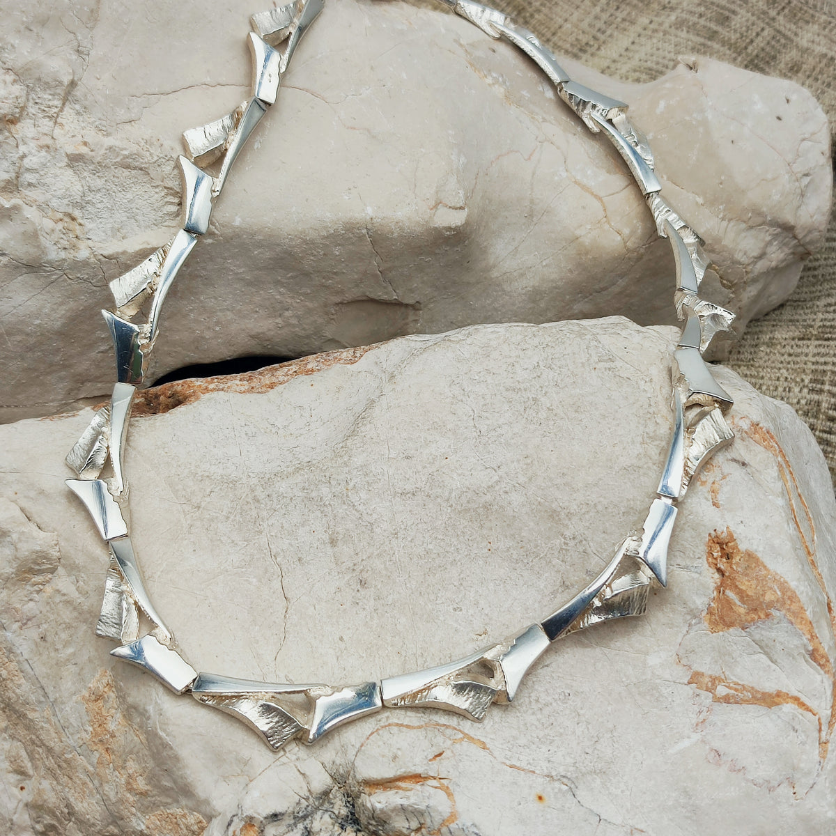 Zilveren Finse schakelketting van Marjut Kemppi voor Tammen Koru, met gebogen schakels in hoogglans en een ruwe structuur.