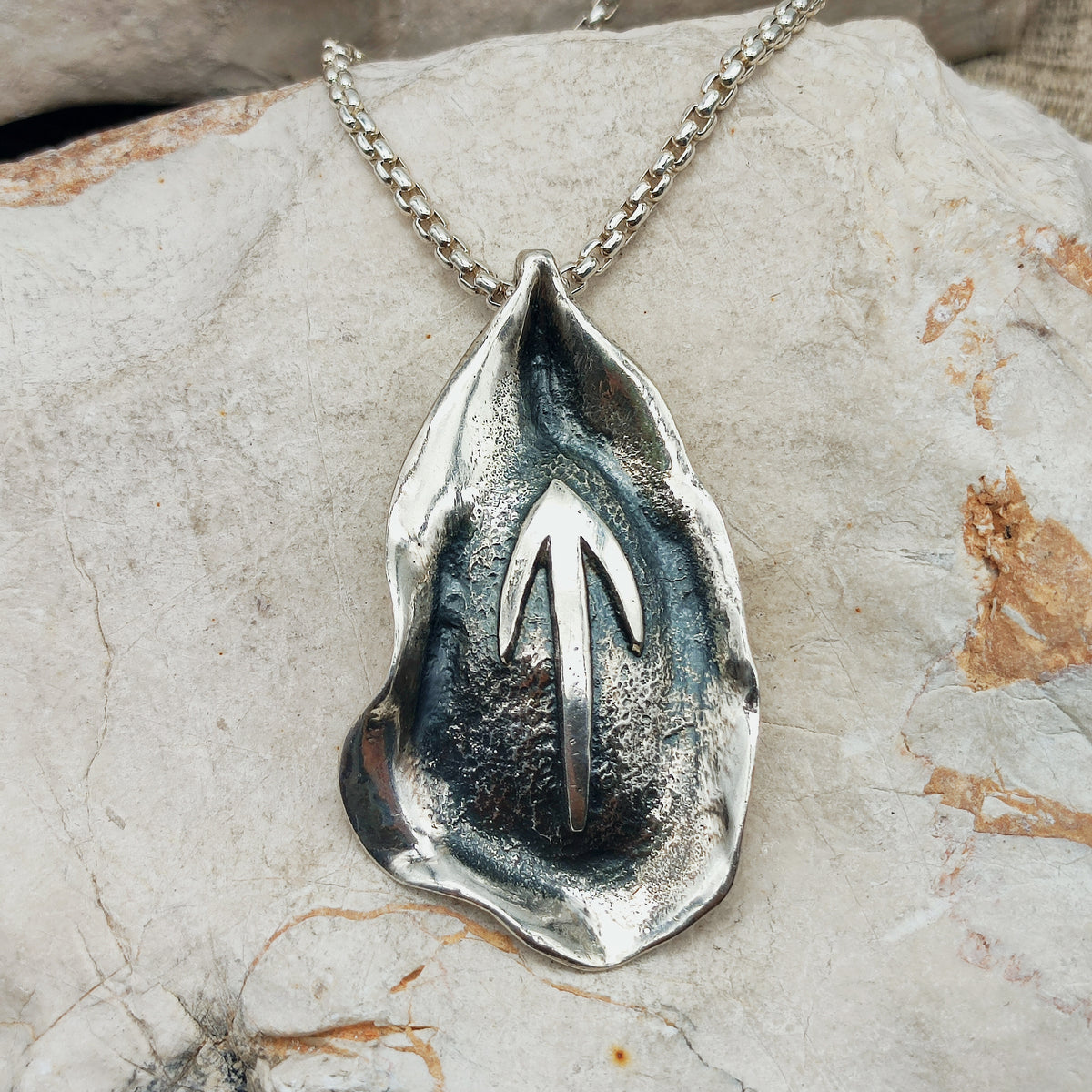 Grote abstracte sterling zilveren hanger van Mies De Wilde met geoxideerde structuur en pijlvormig reliëf aan een Venetiaanse ketting.
