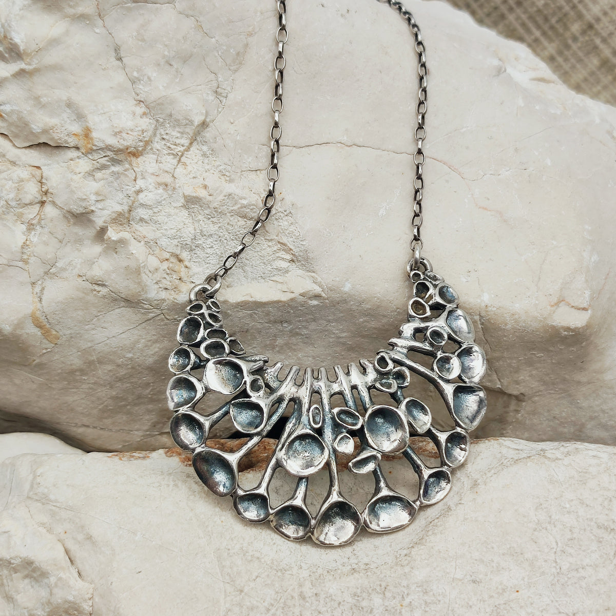 Lange vintage zilveren ketting van Hannu Ikonen voor Valo-Koru Oy met een halvemaanvormig middenstuk in rendiermosmotief.